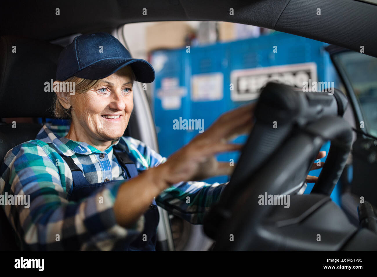 Senior meccanico femmina la riparazione di un auto in un garage. Foto Stock