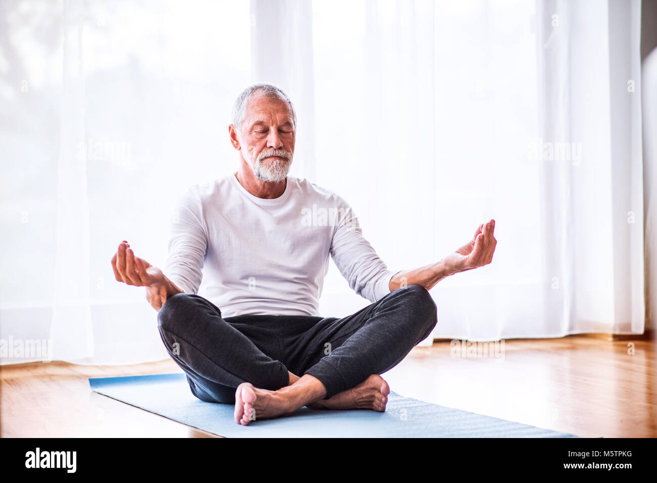 Senior uomo meditando a casa. Foto Stock