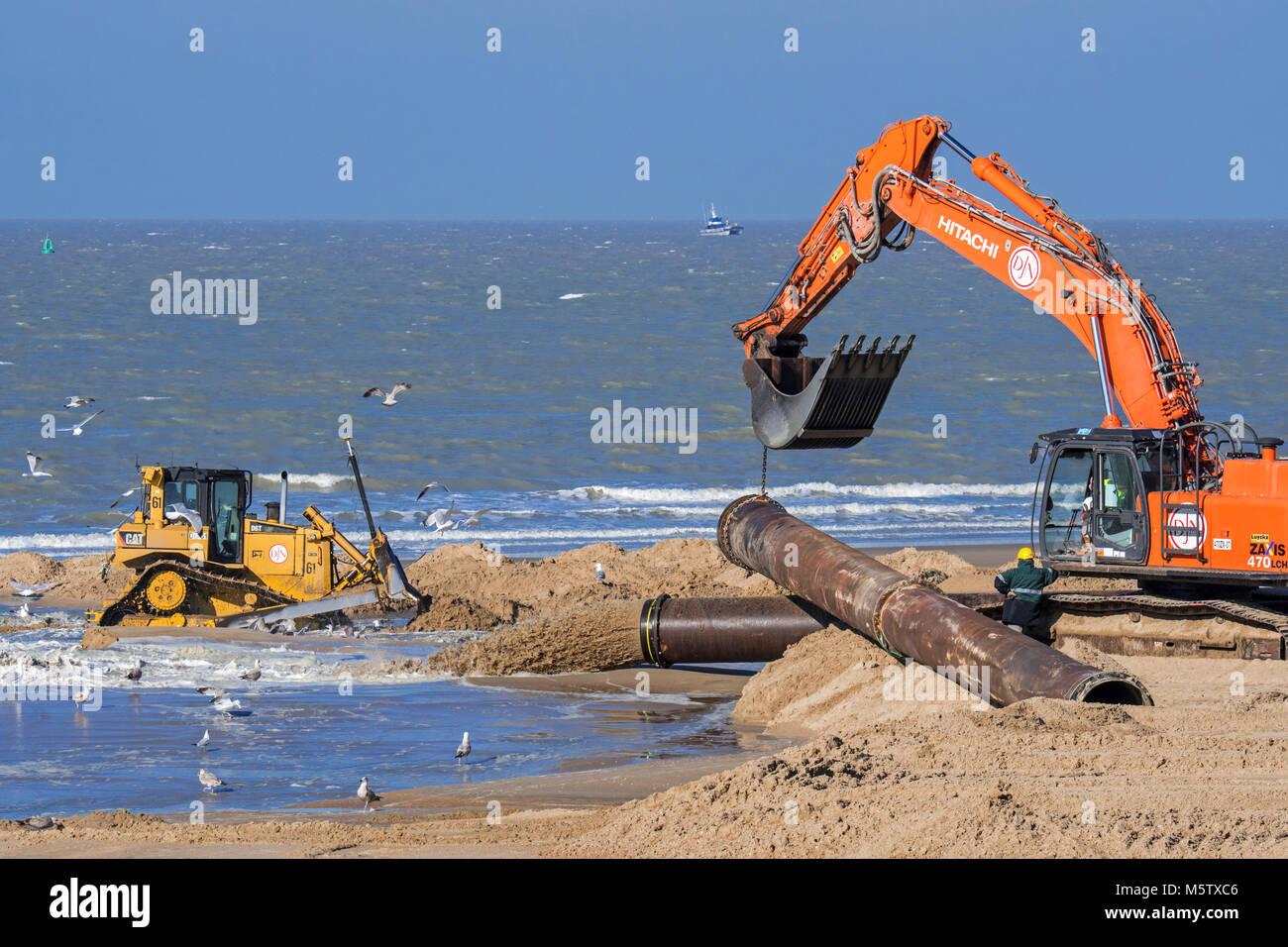 Bulldozer e escavatore idraulico installazione tubazione durante il rifornimento di sabbia / spiaggia nutrimento lavora lungo la costa belga di Ostenda, Belgio Foto Stock