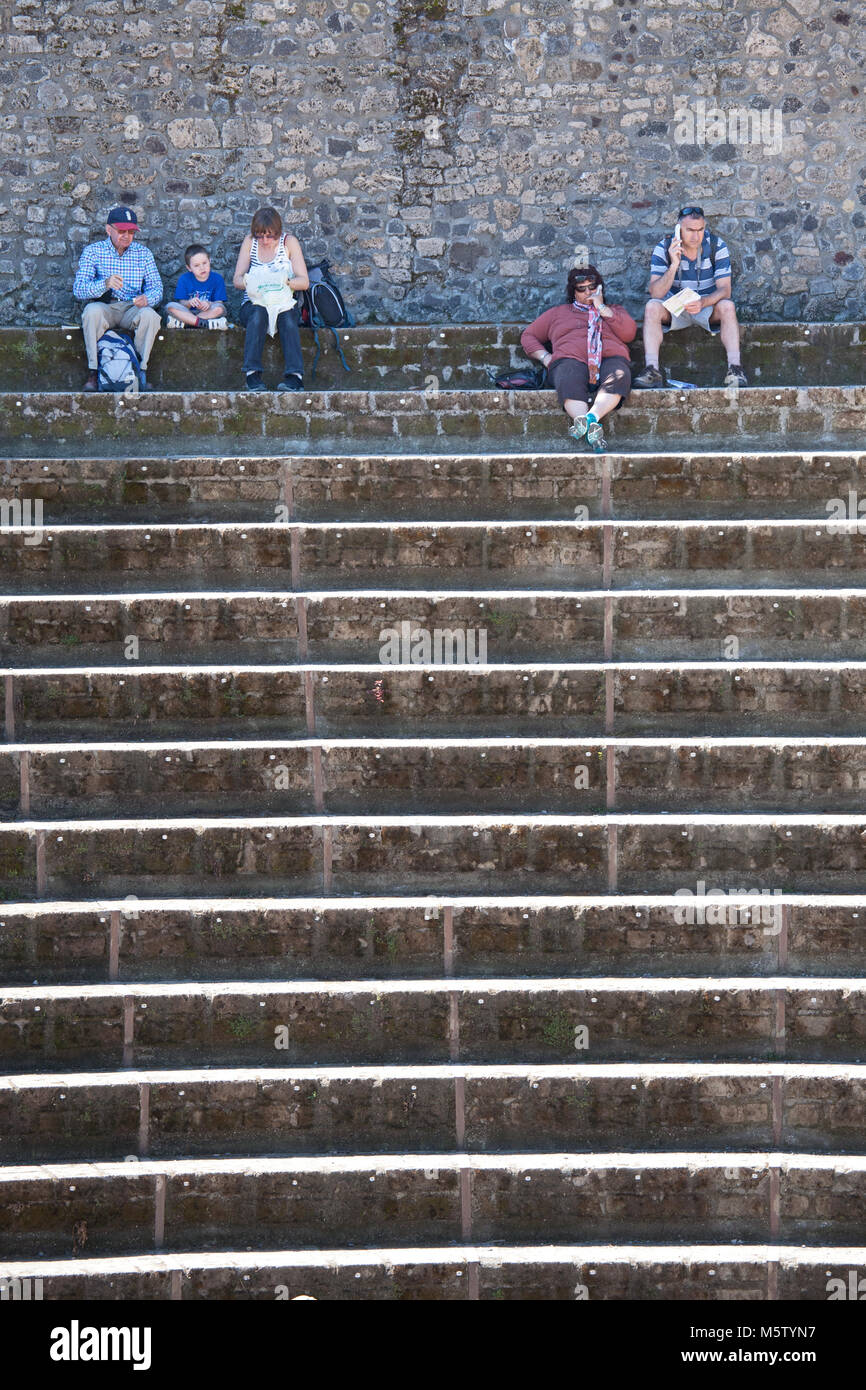 Turisti che si siedono sui gradini del Teatro Grande di Pompei, Italia. Foto Stock