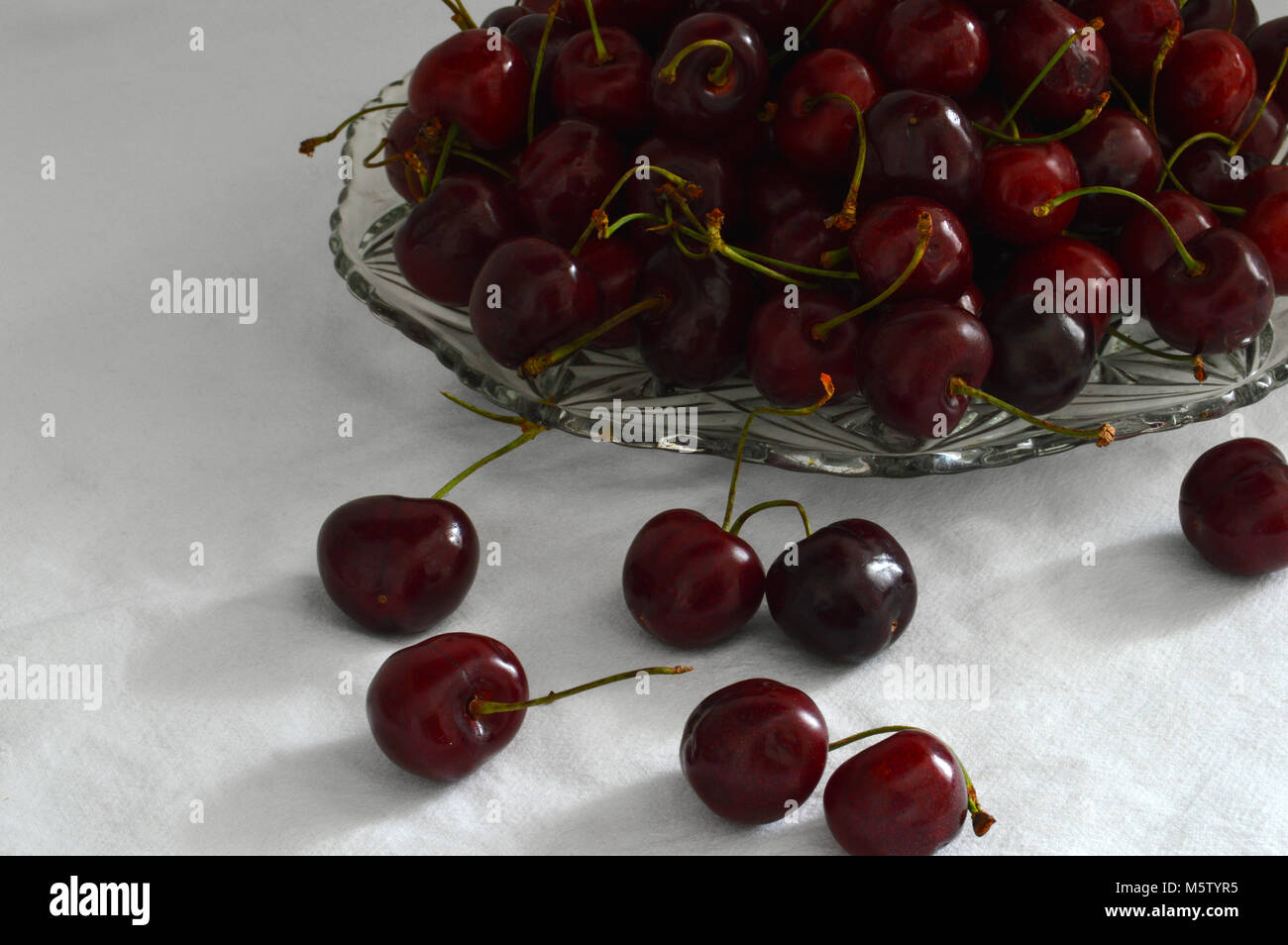 Ancora in vita con una lastra di vetro con ciliege rosse su sfondo bianco Foto Stock