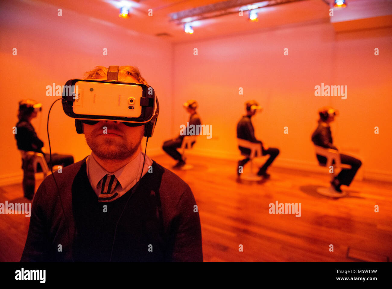 La gente reale utilizzo interattivo di realtà virtuale di cuffie e auricolari in una galleria d'arte Foto Stock