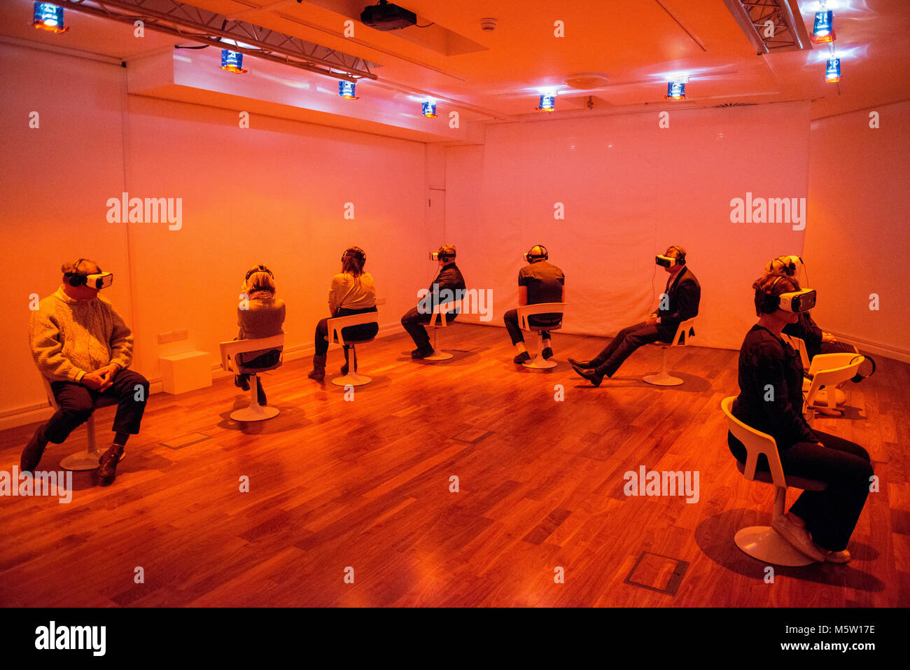 La gente reale utilizzo interattivo di realtà virtuale di cuffie e auricolari in una galleria d'arte Foto Stock