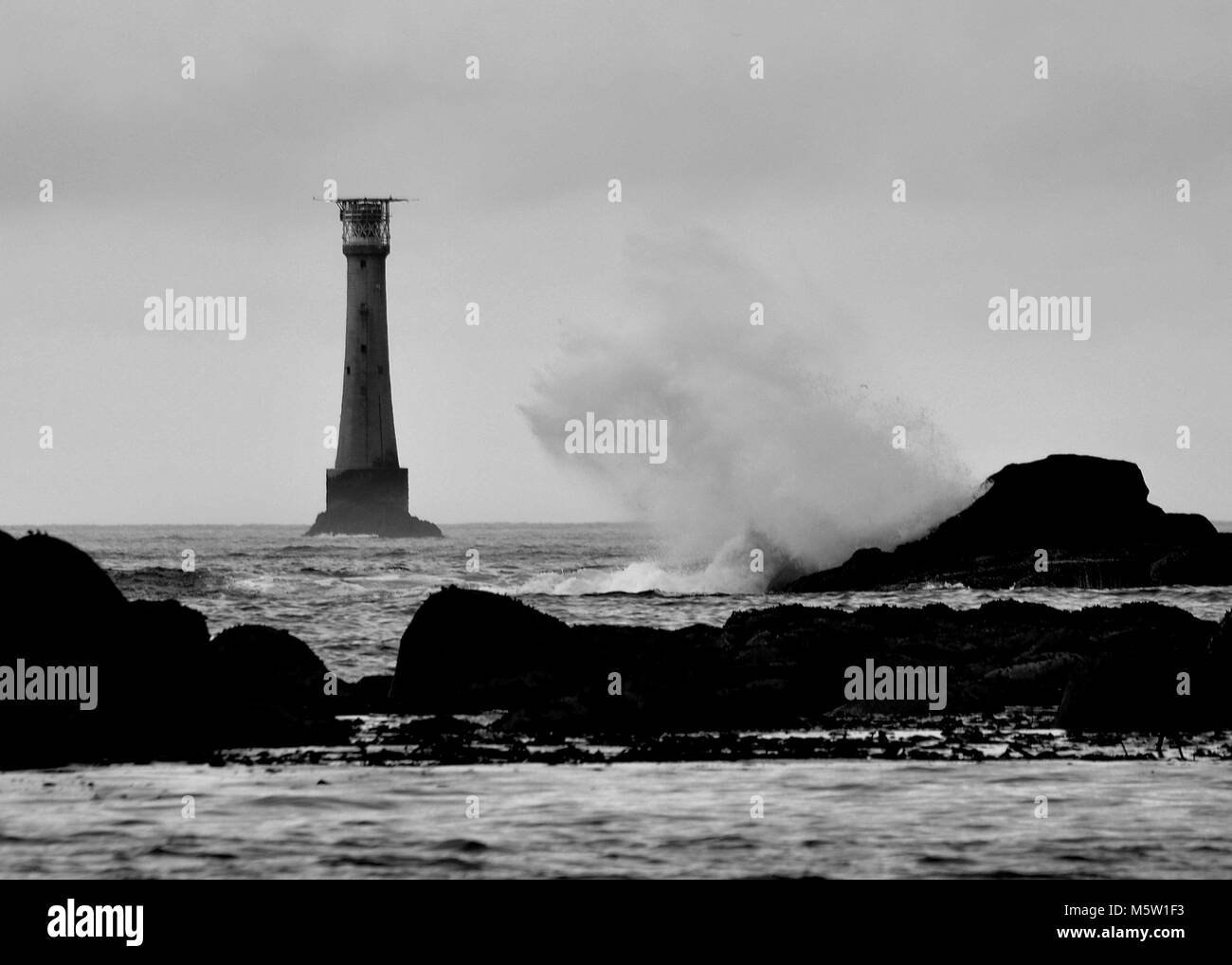 Mare tempestoso con grandi onde che si infrangono contro le rocce, bianco e nero. Bishop Rock, Isles of Scilly, Regno Unito Foto Stock