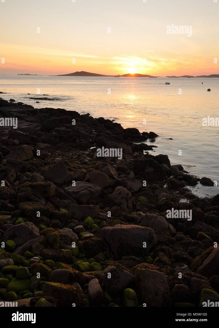 Tramonto sul mare attraverso la costa rocciosa. Isole di Scilly, vista sul mare fino all'isola di Samson al tramonto. Foto Stock