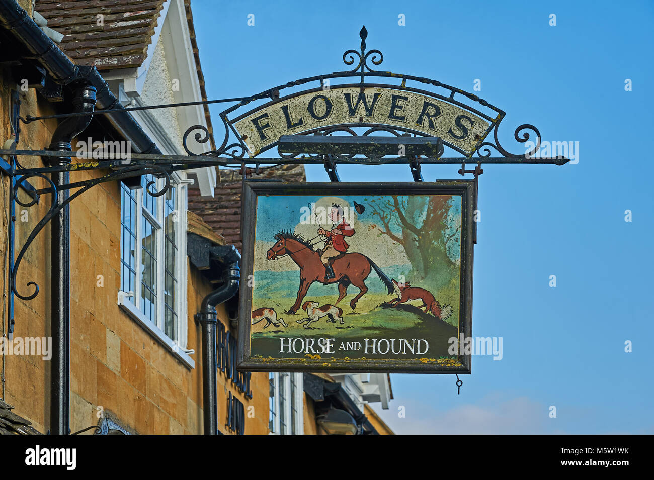 Vecchio pub pubblicità segno ales fiori appesi da un pub in Cotswolds città di Broadway. Il pub segno raffigura una immagine di una battuta di caccia a cavallo e cane Foto Stock