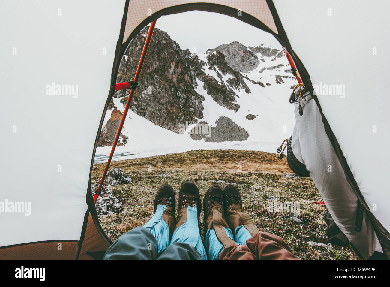 Travel paio di piedi vista montagne dalle tende da campeggio ingresso concetto Lifestyle Vacanze avventura all'aperto Foto Stock