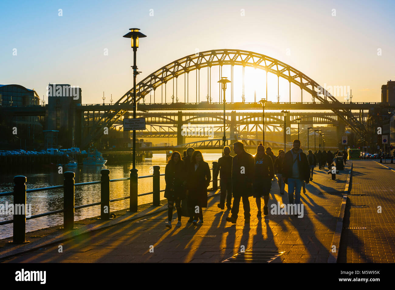 Newcastle Tyne Bridge, vista al tramonto delle persone che camminano in banchina area di Newcastle, Inghilterra, con la mitica Tyne Bridge in background, REGNO UNITO Foto Stock
