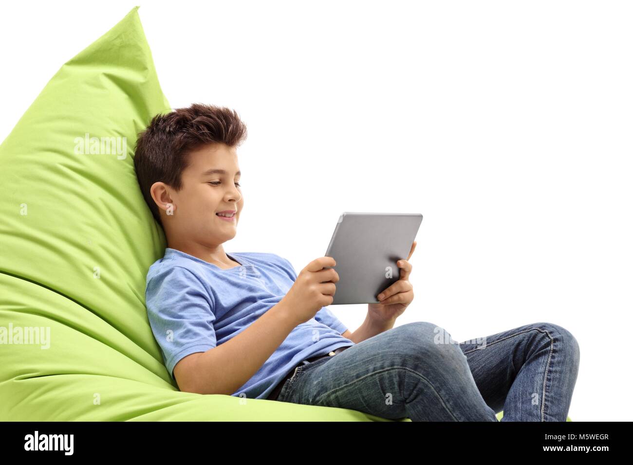 Ragazzo seduto su un verde beanbag utilizzando un tablet isolati su sfondo bianco Foto Stock
