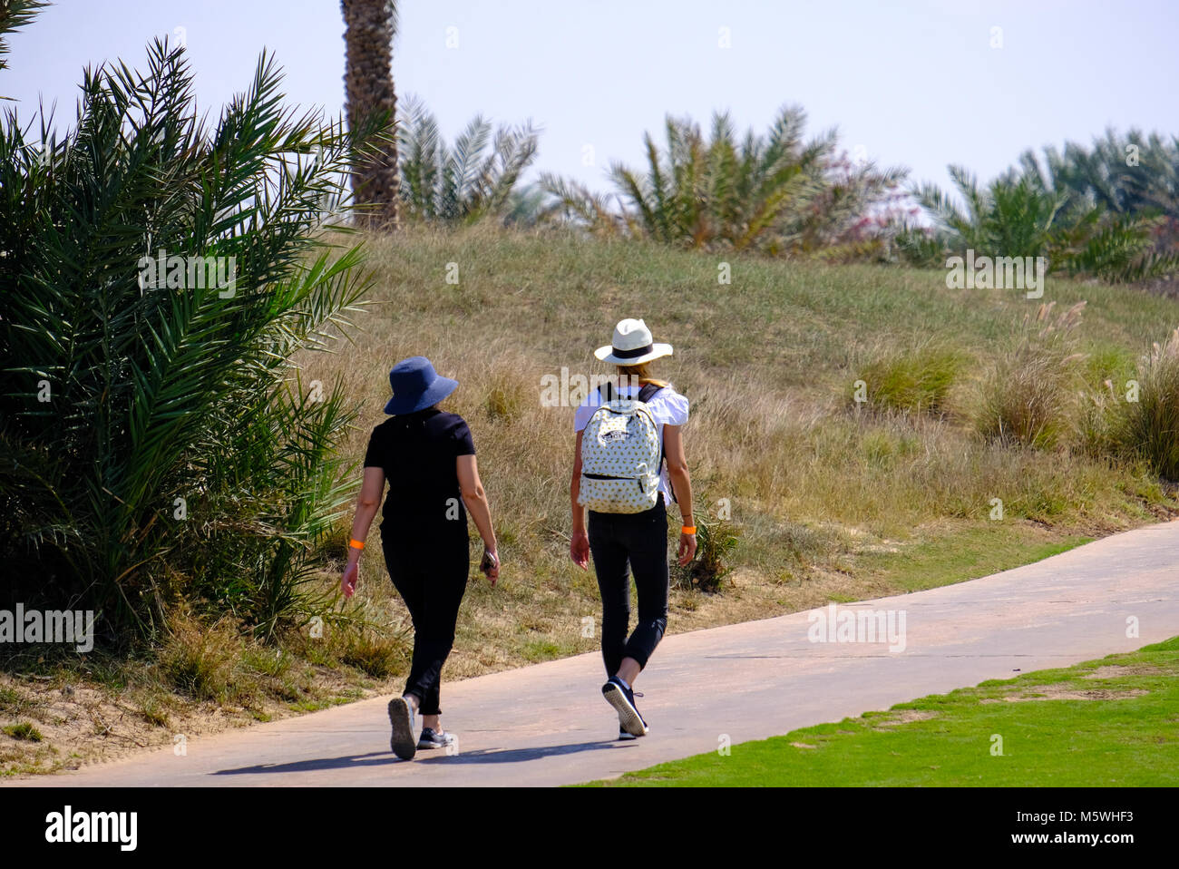 Due giovani donne camminando sulla pista da jogging a Saadiyat Island Golf Course, Abu Dhabi Foto Stock