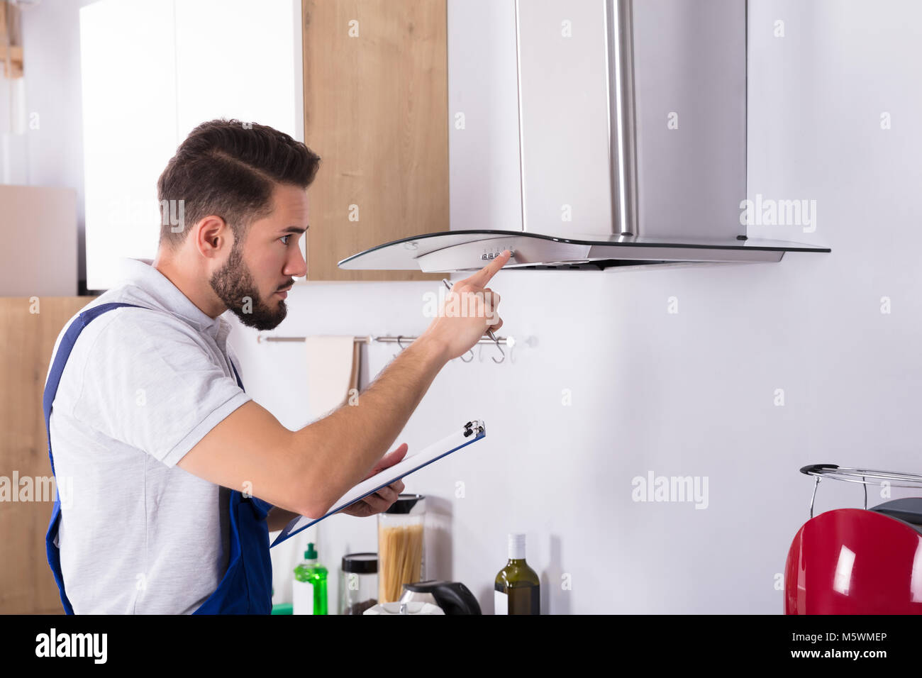 Elettricista maschio con appunti riparazione cucina filtro estrattore Foto Stock