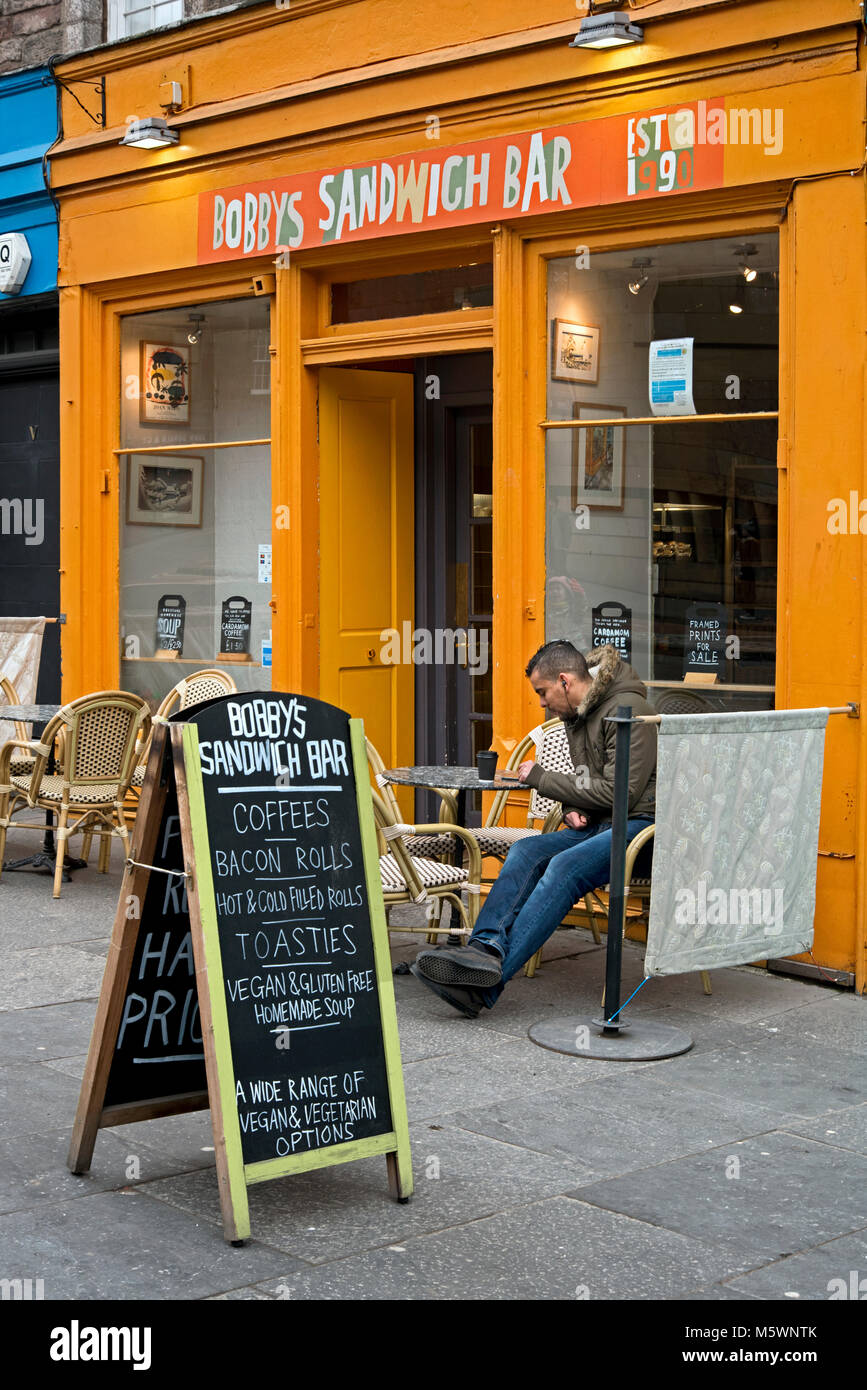 Un cliente seduto fuori Bobby's Bar Sandwich a Edimburgo, Scozia. Foto Stock