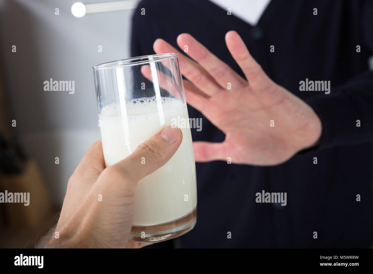 Close-up di mano di una persona di rigetto di bicchiere di latte offerto da persona Foto Stock