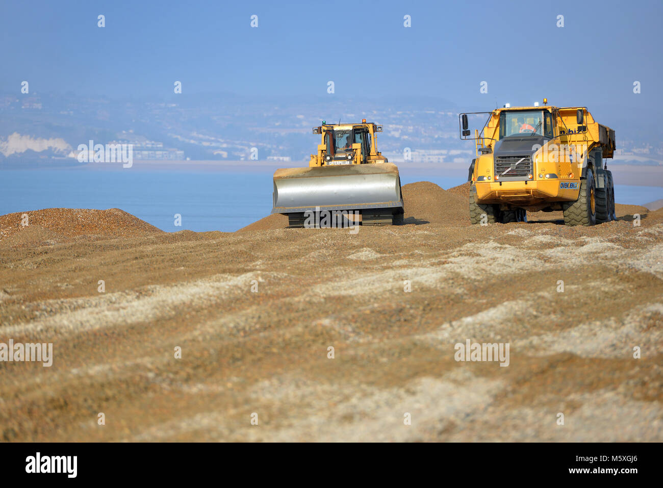 Macchinari pesanti di scandole in movimento sulla spiaggia di Seaford, East Sussex, dopo annuale tempeste invernali erodere la spiaggia. Foto Stock