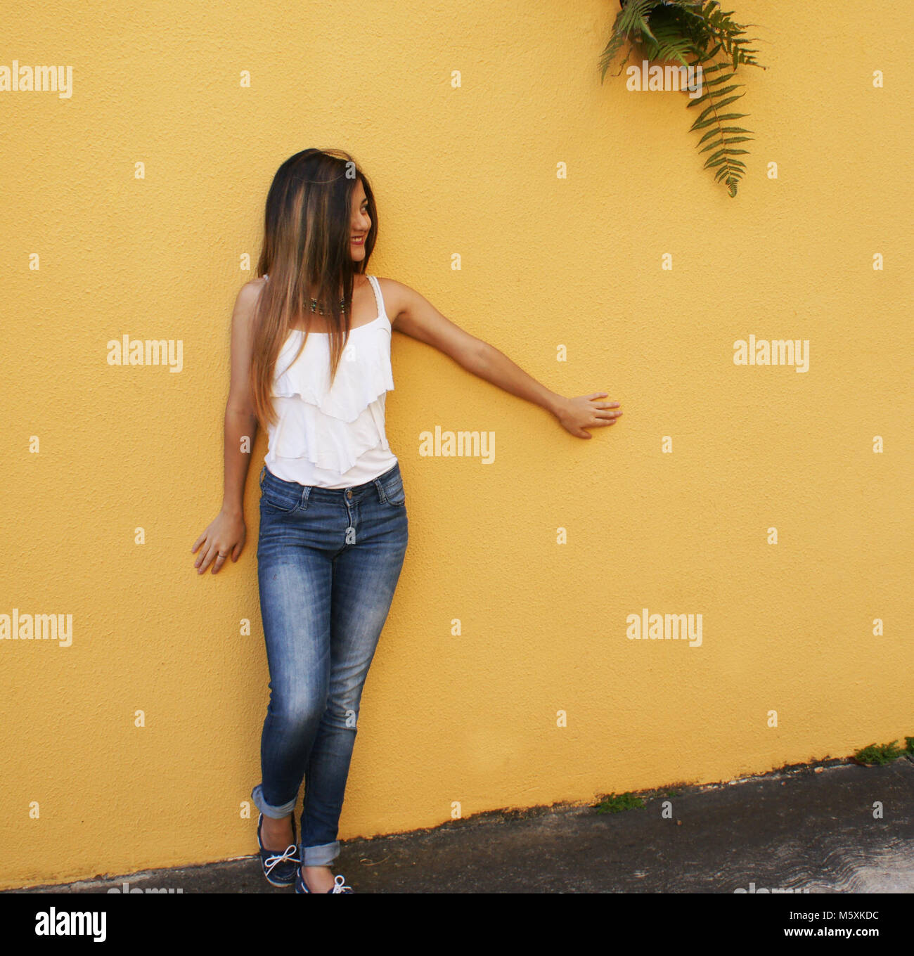 Ragazza su una parete di colore giallo Foto Stock