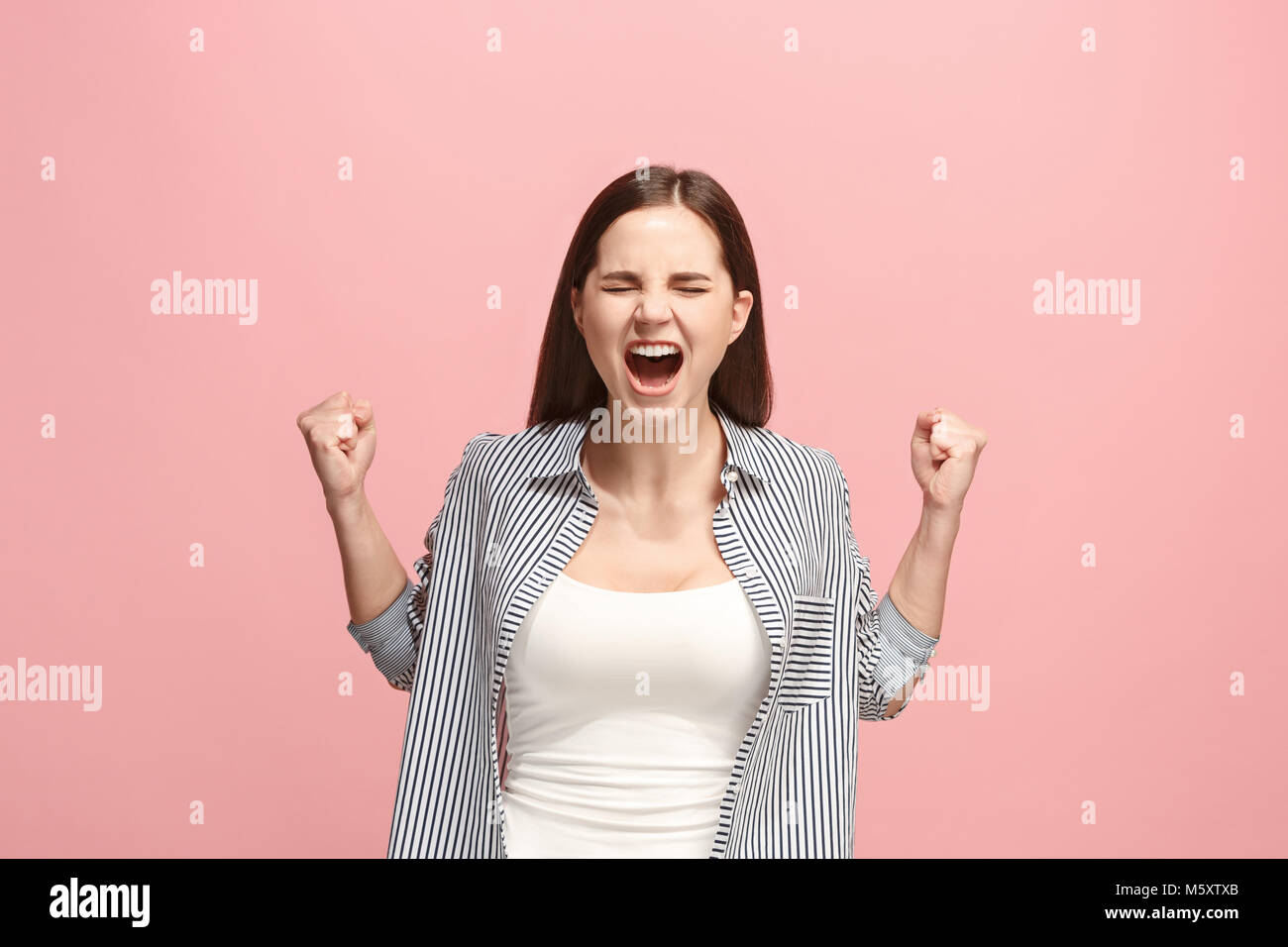 Il giovane arrabbiato emotiva donna urlando in rosa di sfondo per studio Foto Stock