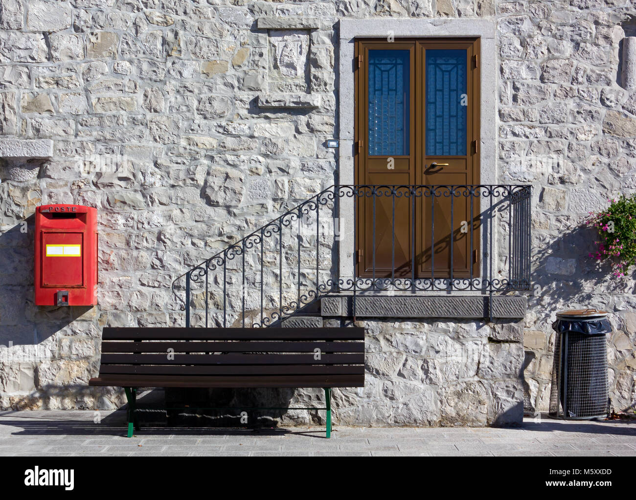 Il marciapiede con una panca, scale per una casa della porta anteriore, un bidone della spazzatura e una casella rossa Foto Stock