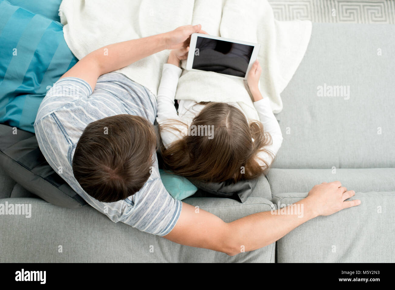 Al di sopra di vista del padre utilizzando digitale compressa godendo di sera con la figlia adolescente e guardare film, spazio di copia Foto Stock