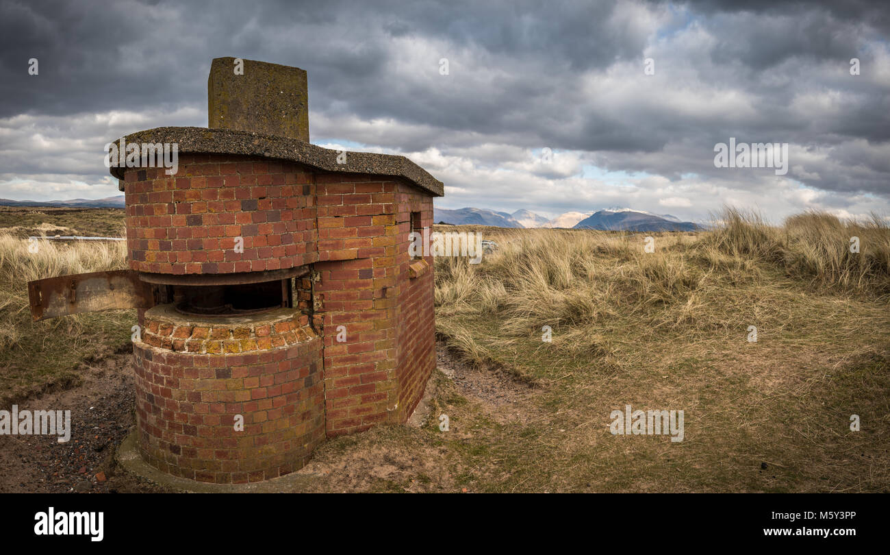 Una vecchia guerra tempo-gun emplacement su Drigg Beach in West Cumbria, nel Regno Unito con la Lakeland Fells all'orizzonte dietro. Foto Stock