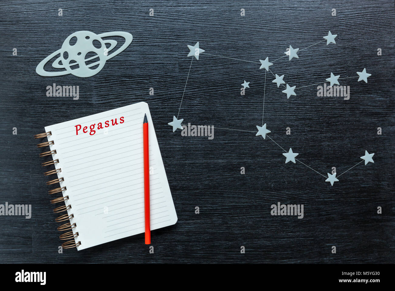 Zodiaco stelle e costellazioni Pegasus su uno sfondo nero con un blocco note e matita. Foto Stock