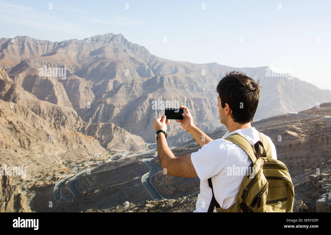 Uomo di scattare una foto del Jabal Jais mountain range visualizza Foto Stock