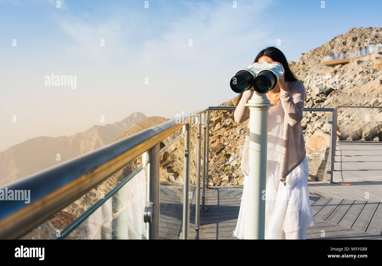 Femmina guardando la gamma della montagna vista dal pubblico binocolo Foto Stock