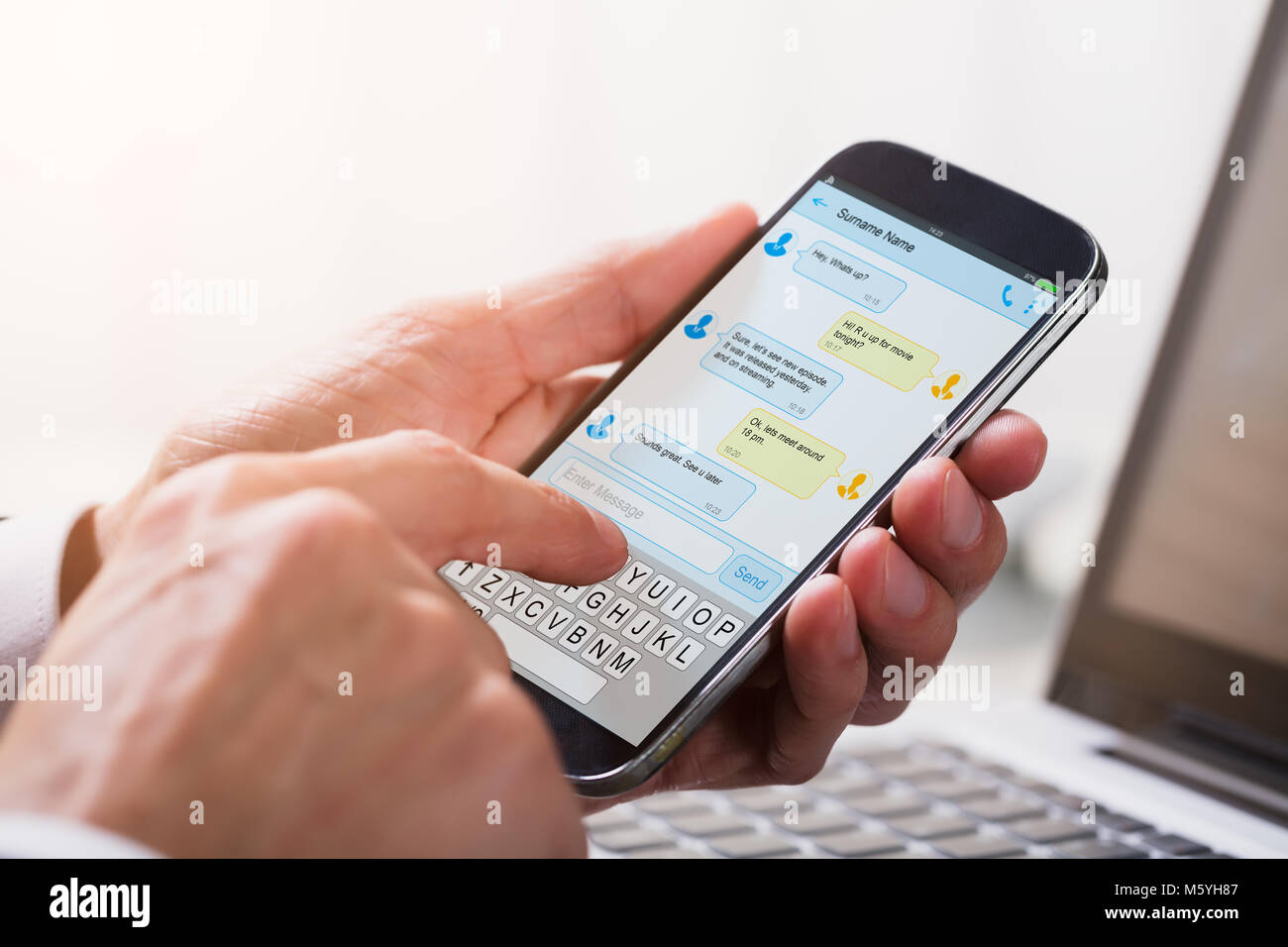 Close-up di un imprenditore la mano di inviare messaggi di testo dal telefono cellulare Foto Stock