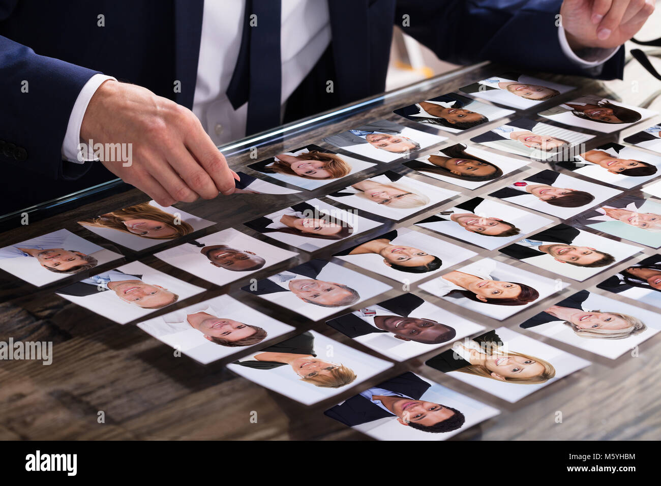 Close-up di commercianti scegliendo fotografia del candidato sulla scrivania in ufficio Foto Stock