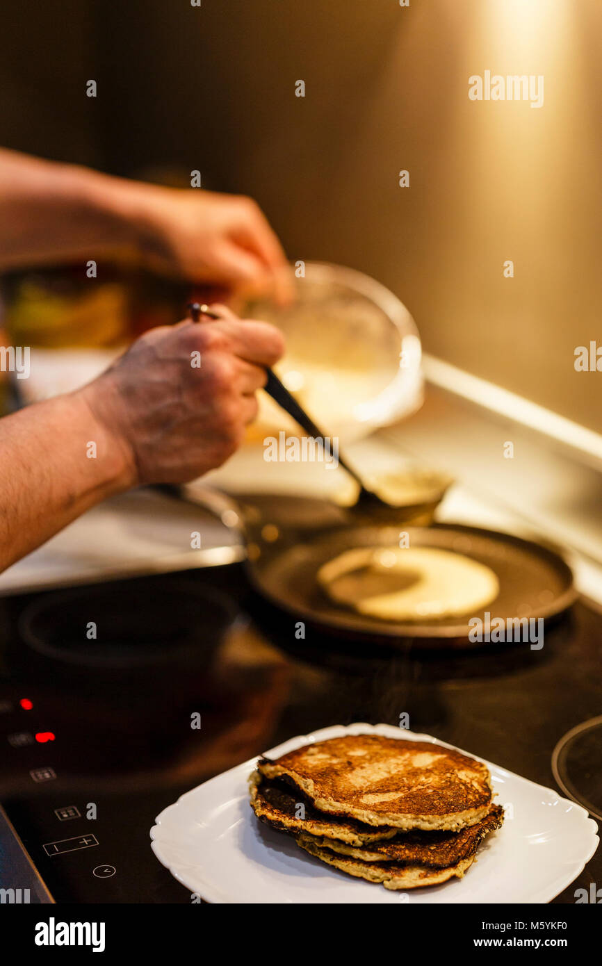 L'uomo cucinare frittelle sul fornello di gamma Foto Stock