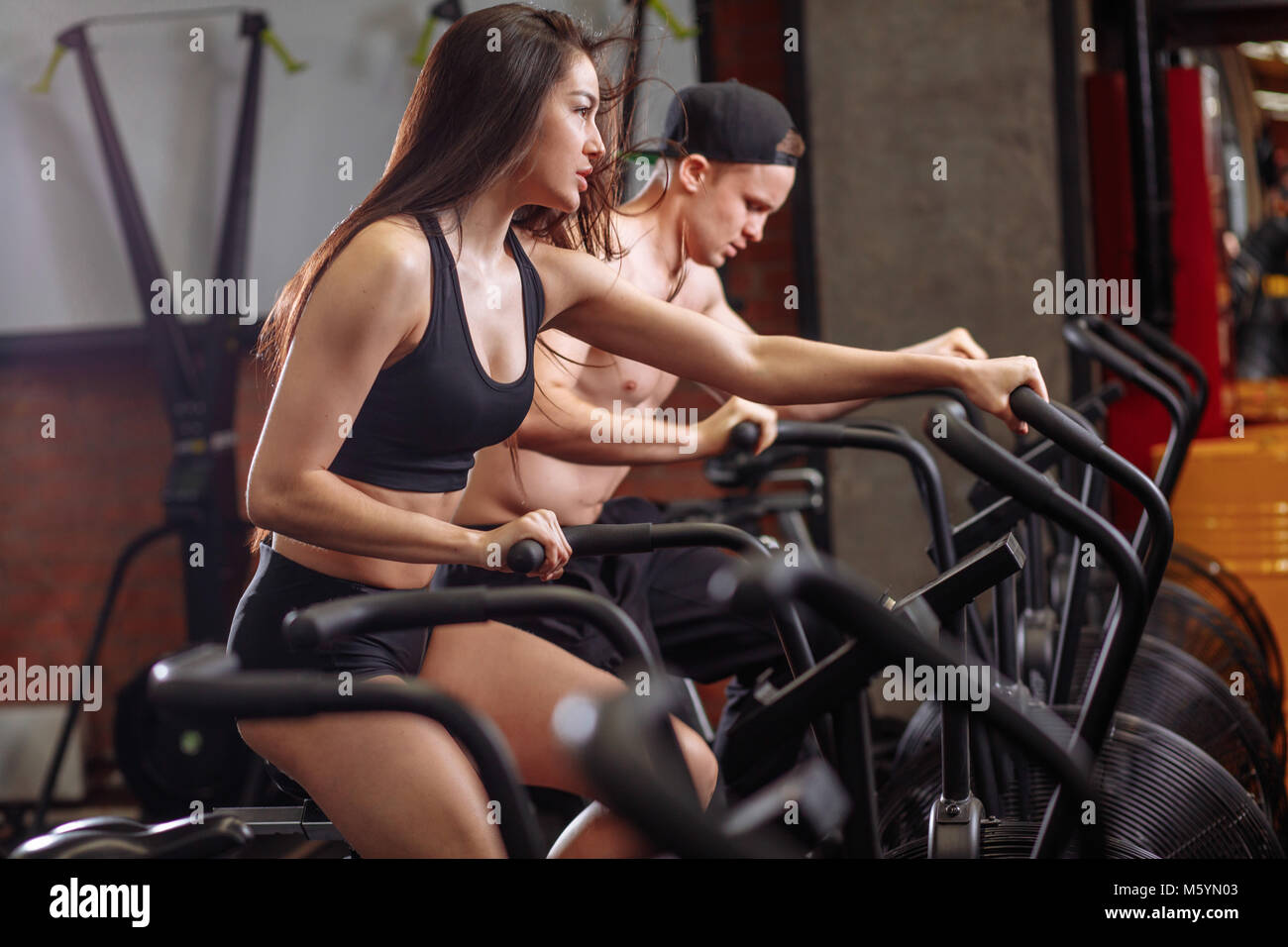 Donna e uomo mountain bike in palestra, esercitando le gambe facendo cardio allenamento ciclismo biciclette Foto Stock