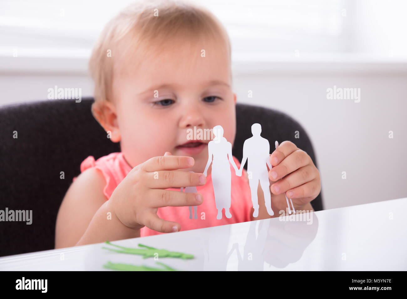 Close-up di un simpatico baby Girl Holding famiglia carta tagliato Foto Stock