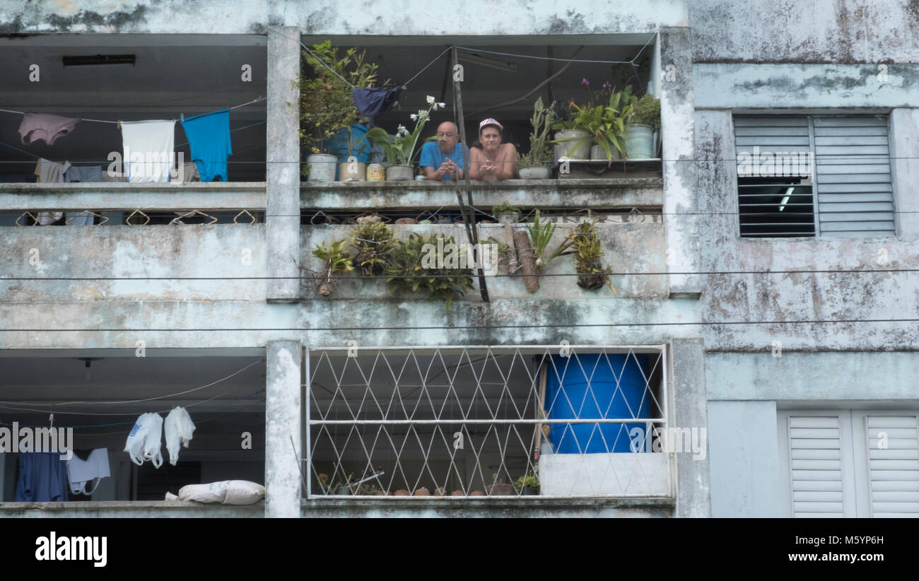 Giovane appoggiata al balcone da thei appartamento edificio Cabarien, Cuba Foto Stock
