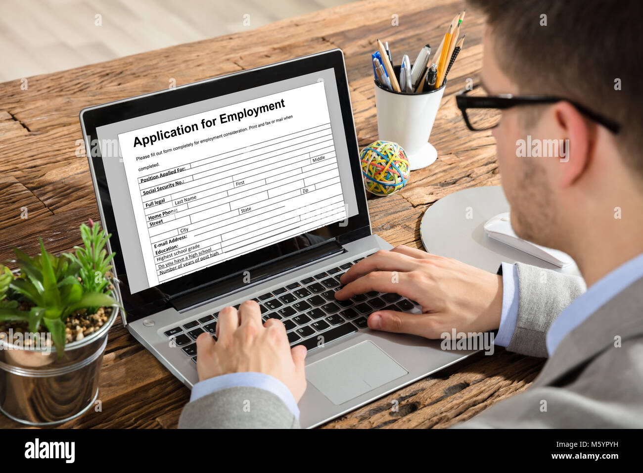 Close-up di un giovane imprenditore applicazione di riempimento per modulo di assunzione su laptop al lavoro Foto Stock