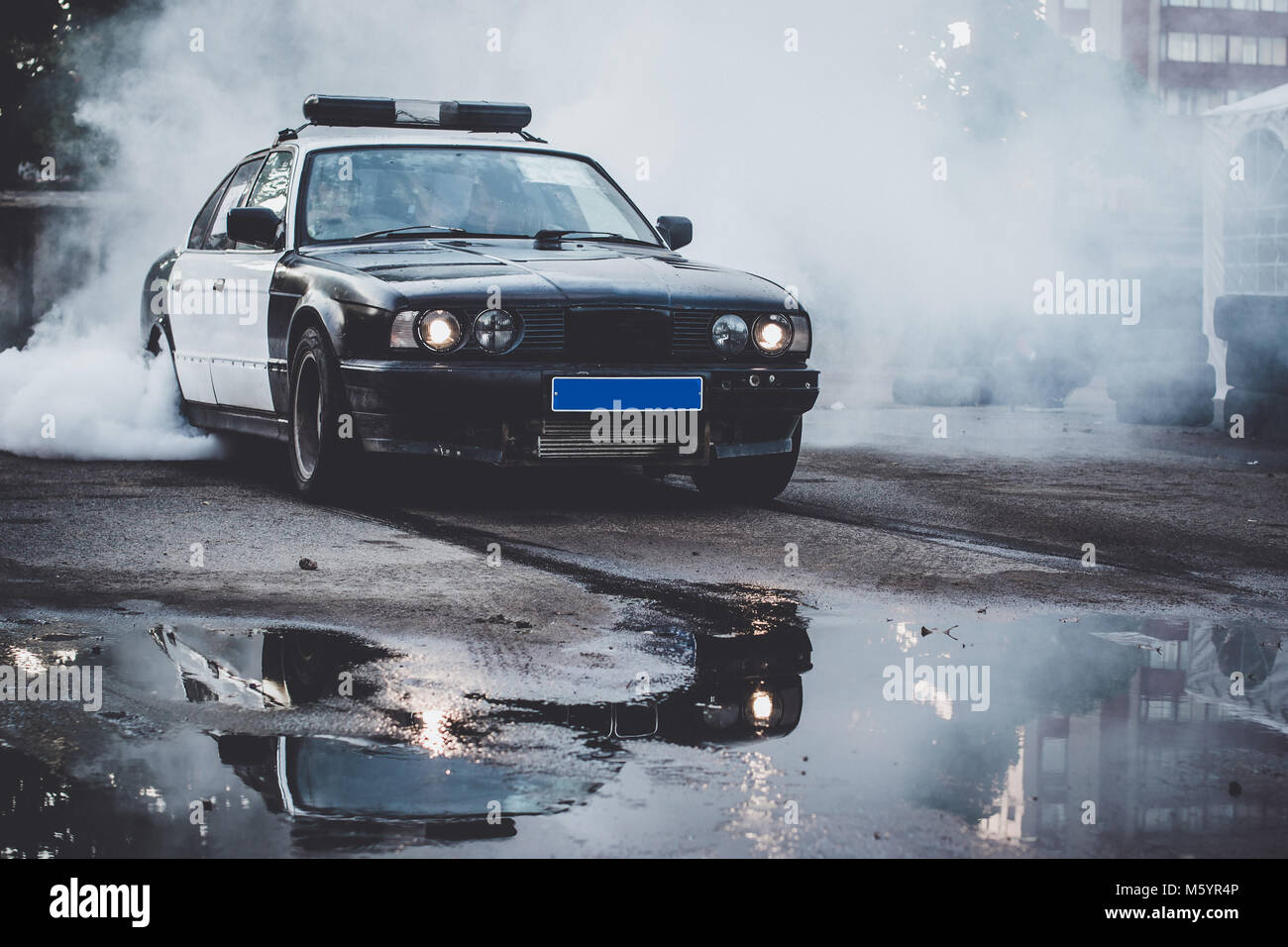 Auto della Polizia sul drift racing motorsport. Il tedesco driftcar bruciando pneumatici su asfalto in drift-show. Velocità, unità e active sport Foto Stock