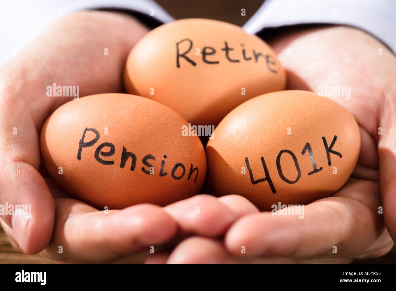 Close-up di una mano umana con uovo marrone che mostra Pensione e testo Foto Stock