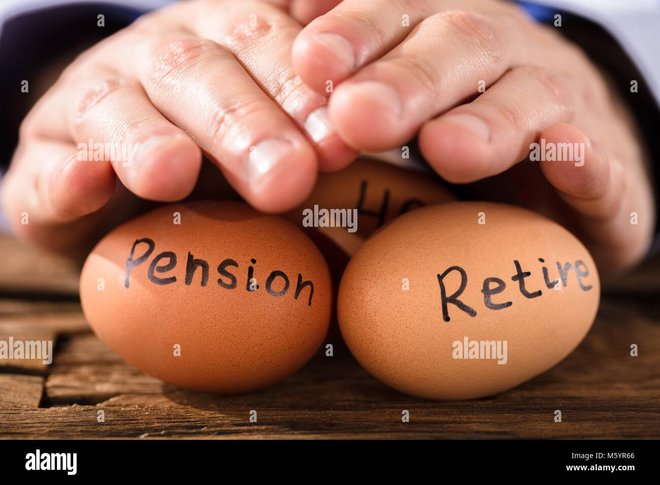 Close-up di mano di una persona la protezione di uova di colore marrone che mostra Pensione e testo Foto Stock