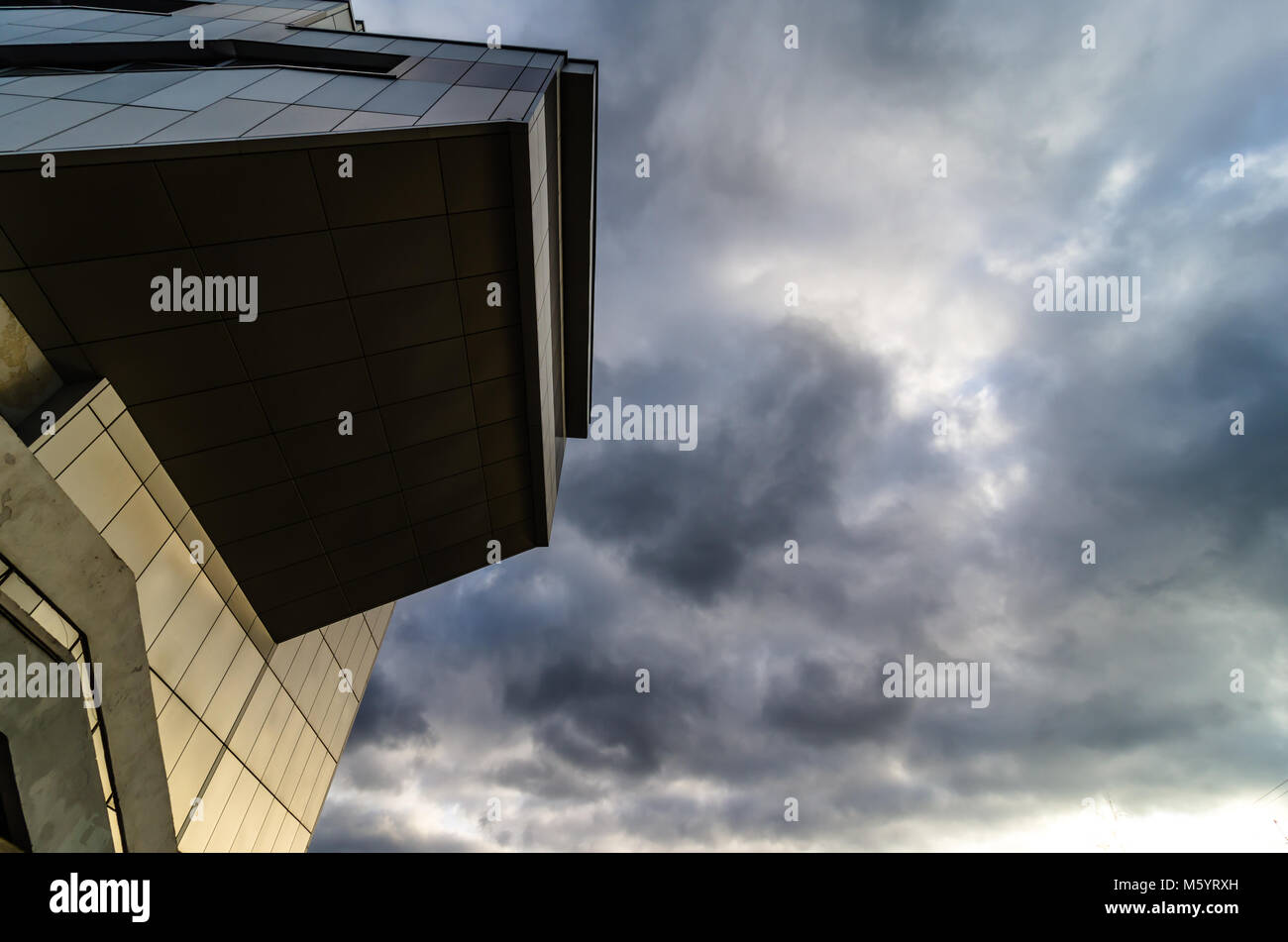 Vista attraverso il moderno ed alto grattacielo in salita verso l'alto al cielo blu con nuvole bianche - abstract architettura dettaglio dello sfondo. Foto Stock