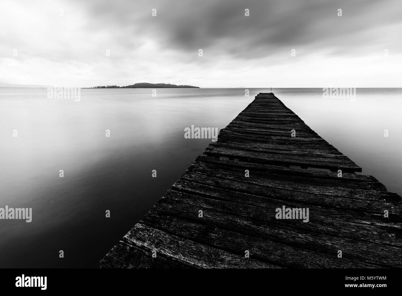 Esposizione lunga prospettiva in prima persona di un molo su un lago, con perfettamente ancora la presenza di acqua Foto Stock