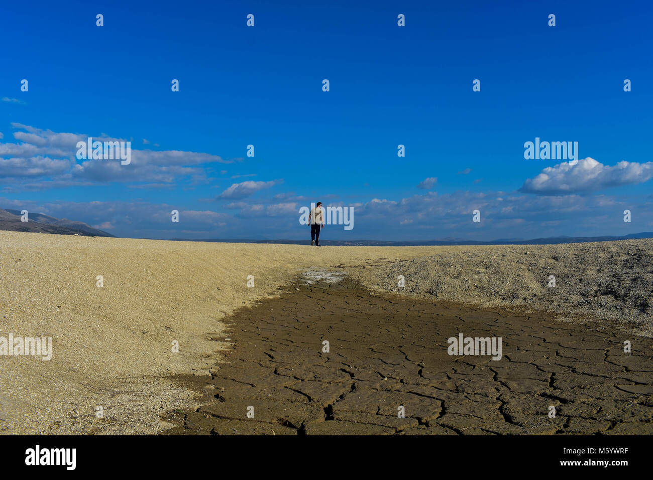 Uomo a piedi a terra asciutta come il deserto con piccolo lago Foto Stock