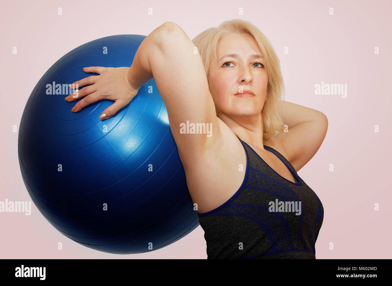 Una donna di mezza età esegue un esercizio con una palla da fitball Pilates Foto Stock
