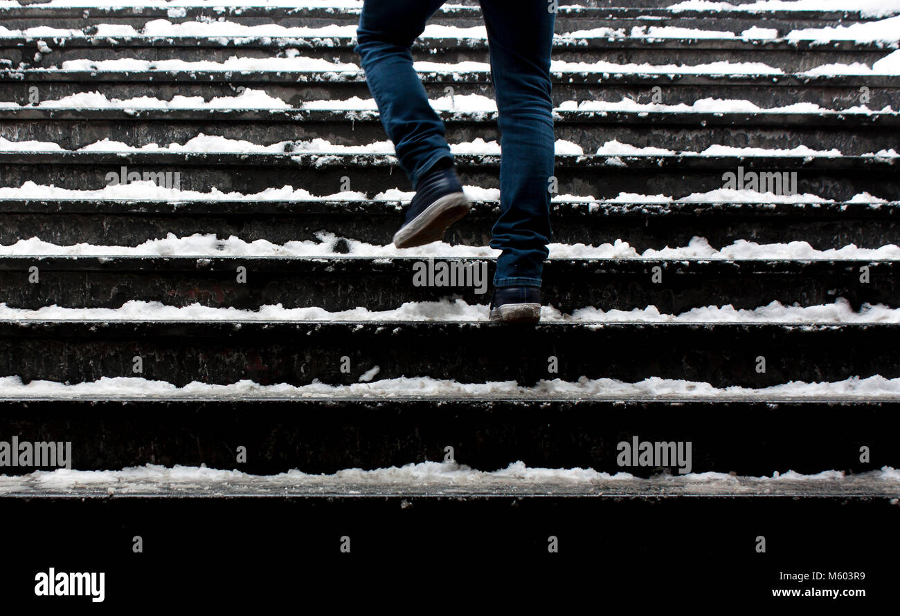 Le gambe di una persona a piedi fino alla scalinata nevoso in motion blur Foto Stock