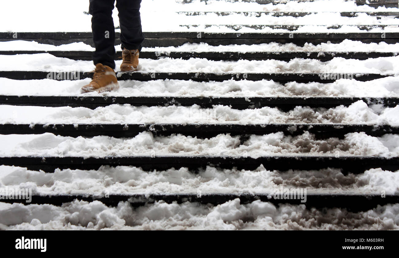 Le gambe di una persona che cammina giù le scale nevoso in motion blur Foto Stock