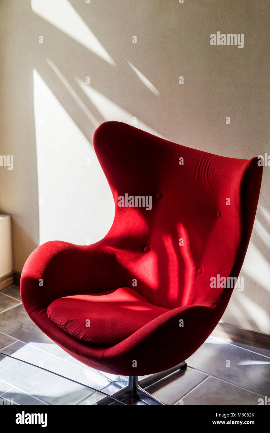 Interessante gioco di luce e ombra su una curva sedia rossa Foto Stock
