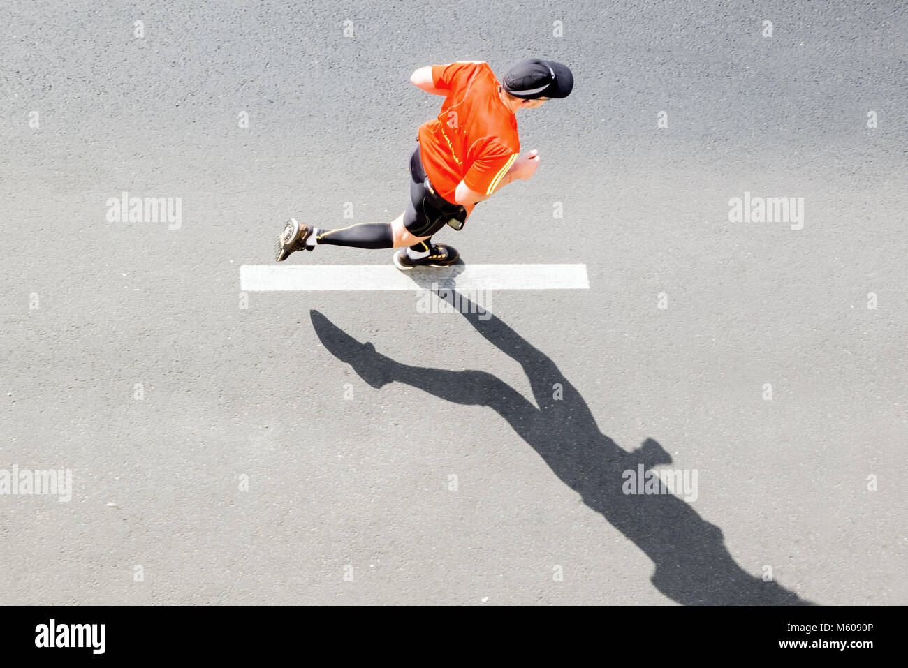 Unico runner in rosso sportswear contro la strada asfaltata con marcatura, vista dall'alto Foto Stock