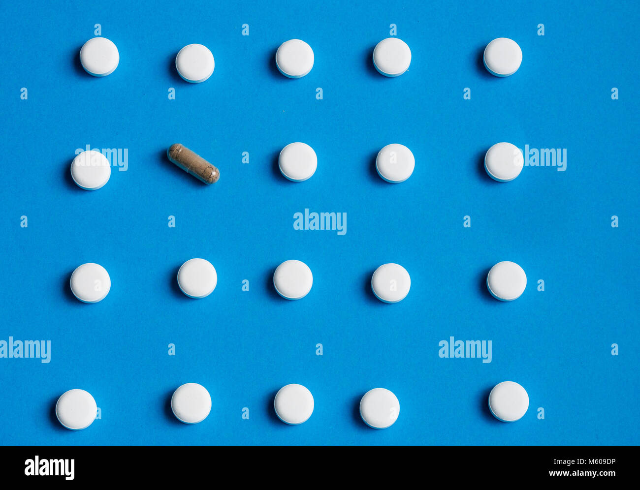 Pillole di bianco e una capsula su sfondo blu (medicina alternativa concetto) Foto Stock