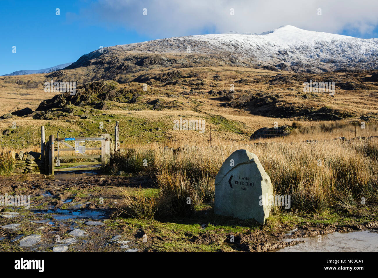 Rhyd DDU sentiero segno e cancello con fango e vista Al Monte Snowdon innevato in inverno nelle montagne di Snowdonia National Park Gwynedd Galles del nord Regno Unito Foto Stock