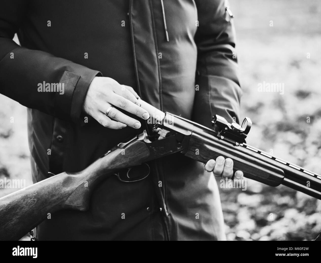 Il fumo dai tronchi di a canna liscia fucile da caccia dopo la cottura. Hunter di camuffamento prende le cartucce da una pistola. In bianco e nero Foto Stock