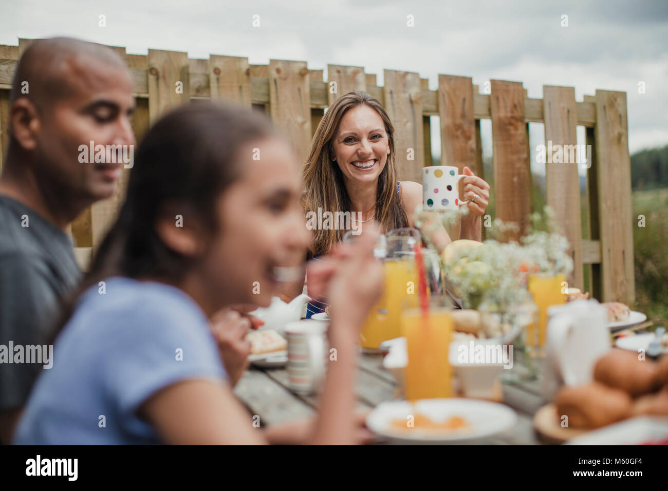 Focus su sfondo di madre sorridente al tavolo della colazione al di fuori. Foto Stock
