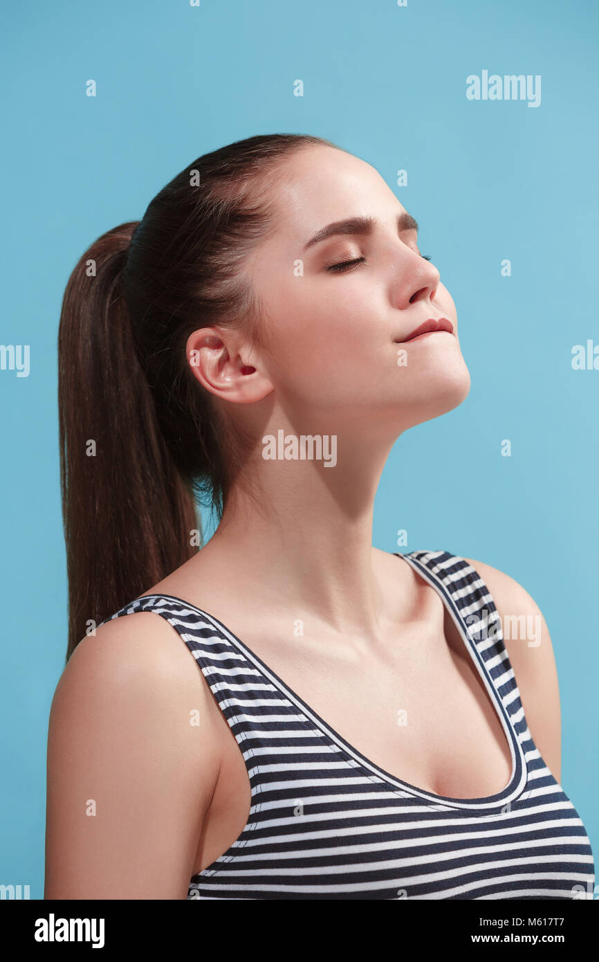 La giovane donna sta cercando di soddisfare su sfondo blu. Foto Stock