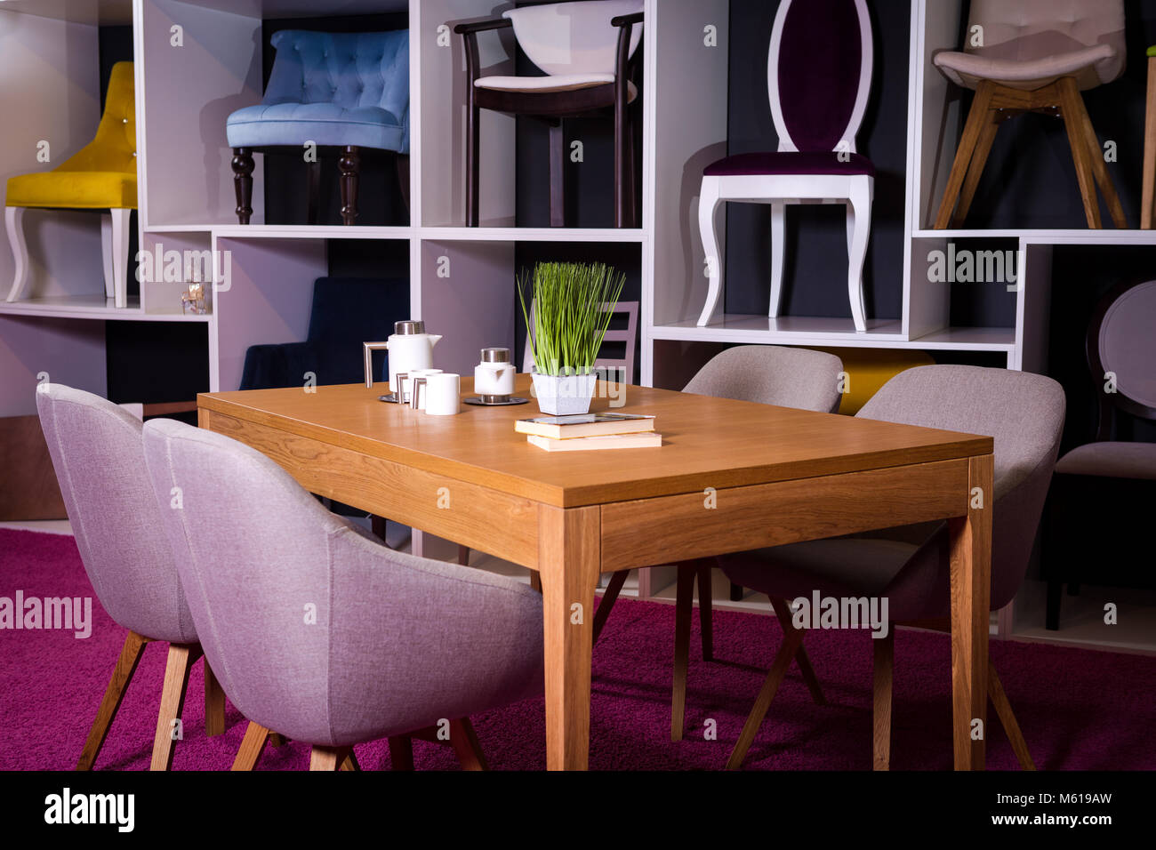 Shop, vendita di mobili in un centro commerciale. Campione di esposizione da pranzo tavolo in legno con sedie di tessili in grigio su un ripiano bianco con mobili e di un Foto Stock